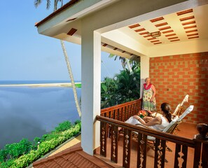 A balcony with a view of the sea, a brick wall, and a wooden railing. - Beach and Lake Ayurvedic Resort (Thiruvananthapuram)