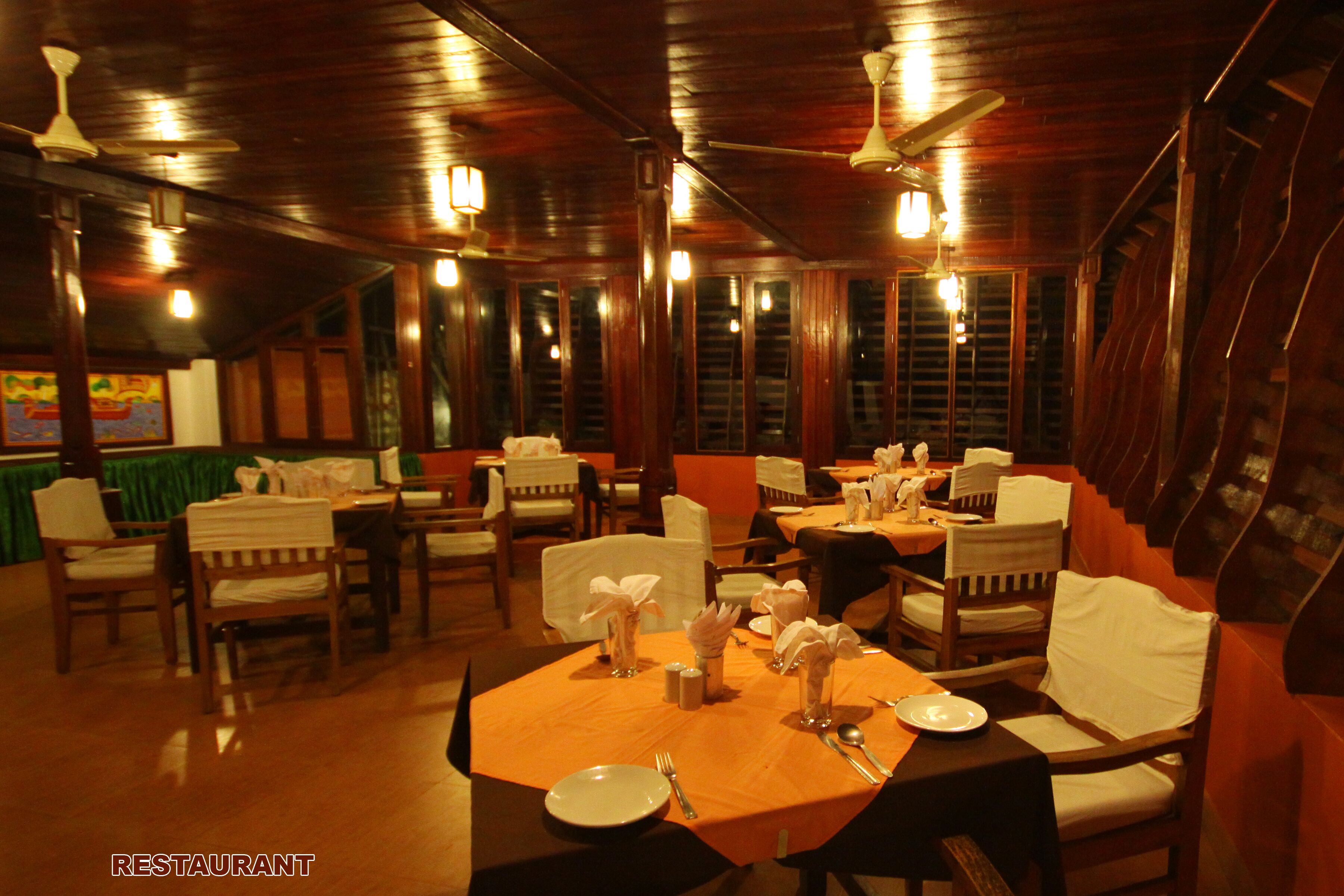 A restaurant with wooden tables and chairs, ceiling fans, and a warm ambiance.