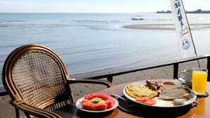 Una mesa con alimentos para el desayuno y vista al mar.