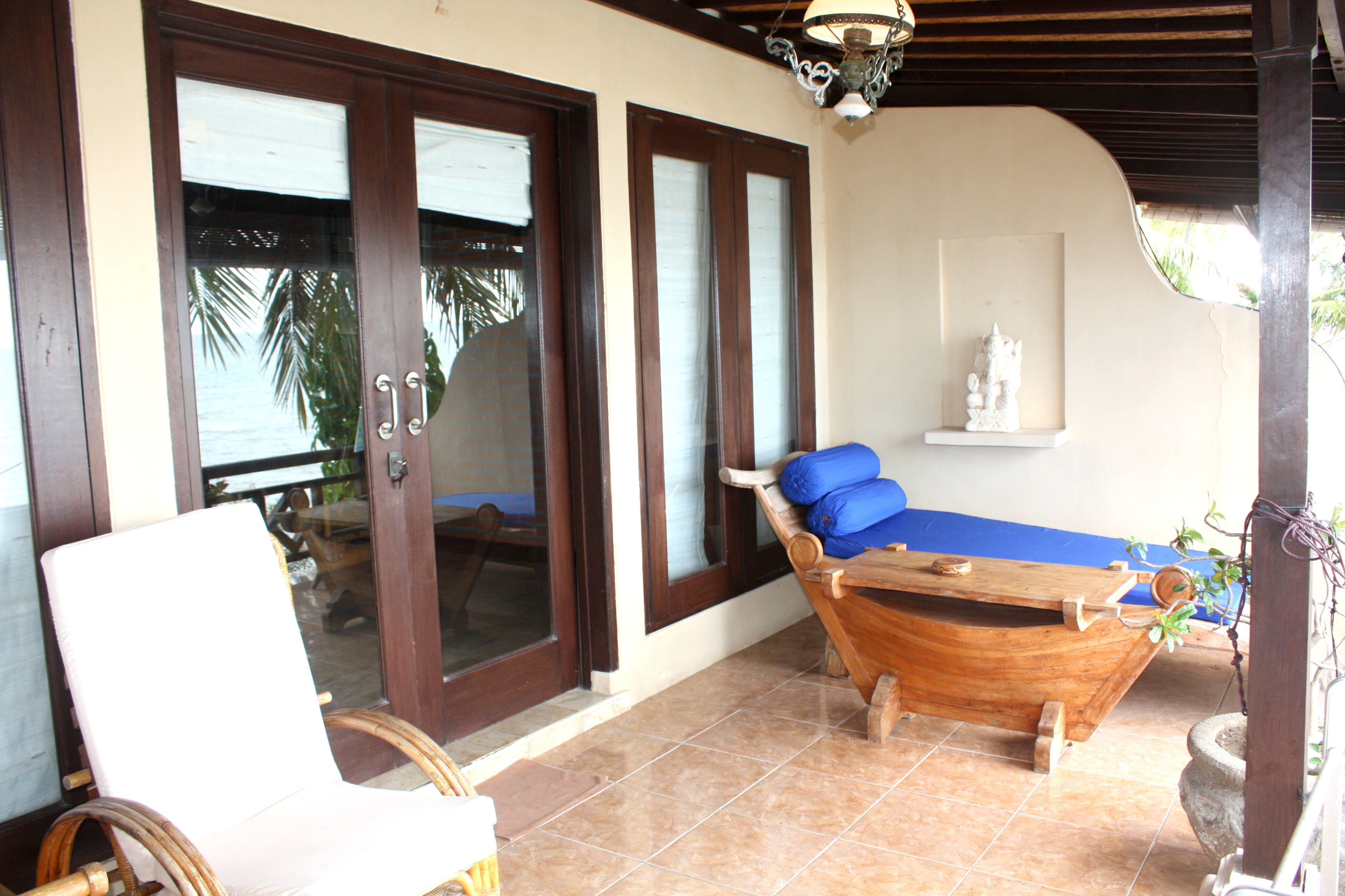 A room with a wooden boat-shaped bed, a white cushioned chair, and a small statue on a shelf.