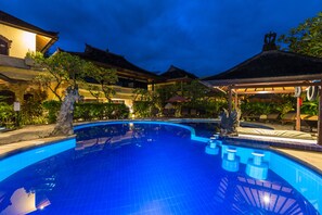 Een buitenzwembad, parasols bij het zwembad en ligstoelen