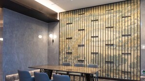 Une salle de conférence moderne, dotée d’une longue table, de quatre chaises et d’un mur décoratif orné de lambris verticaux.