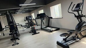 Une salle de sport moderne équipée de divers appareils d’exercice, notamment un tapis de course, un vélo elliptique et des appareils de musculation.