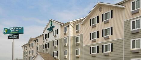 Un hotel de varios pisos con un letrero que indica 'Woodspring Suites' y 'Tarifas por noche disponibles'.