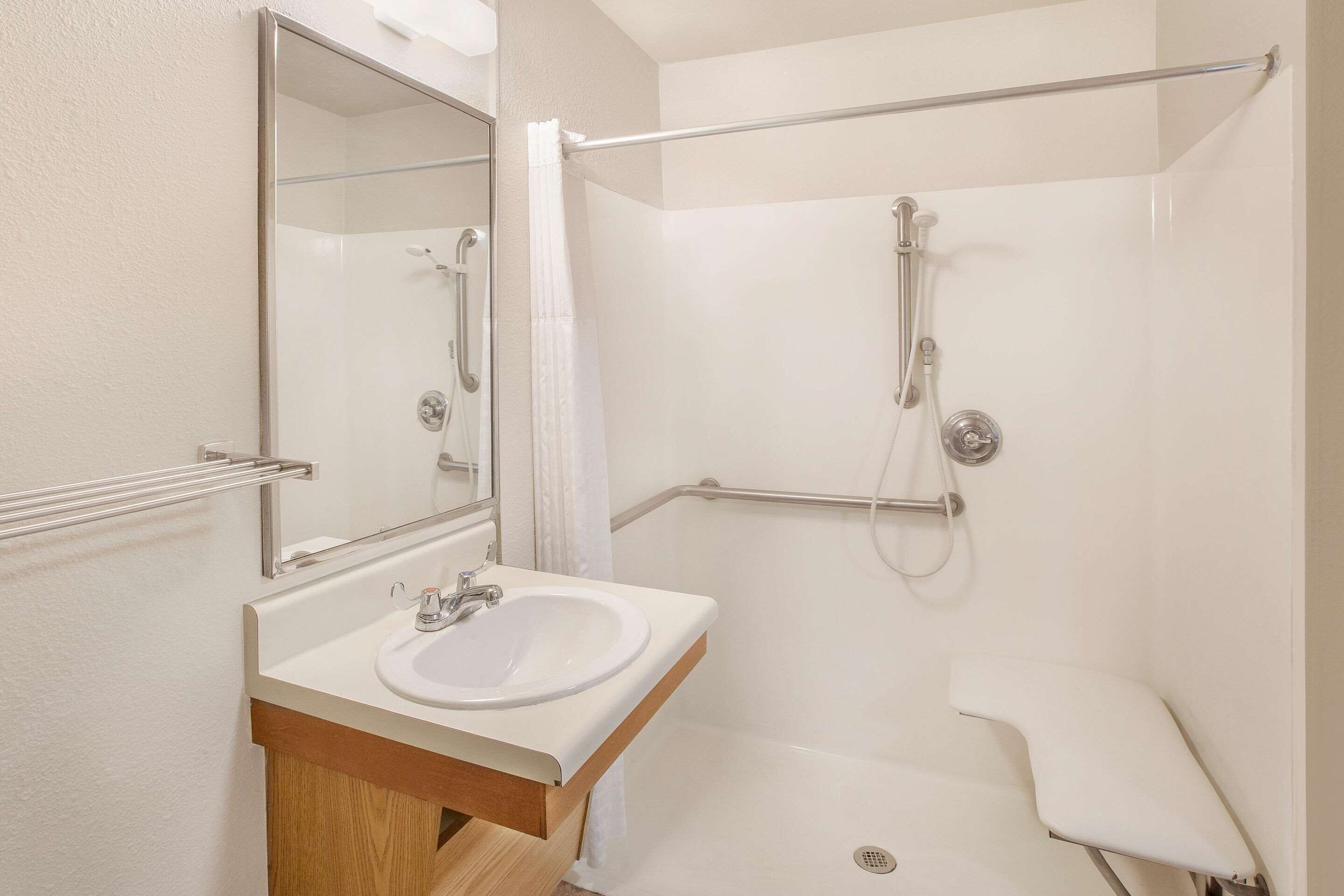 A modern bathroom with a white sink, mirror, and shower.