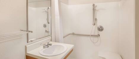 A modern bathroom with a white sink, mirror, and shower.