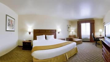 A hotel room with a large bed, a desk, a chair, a television, and two lamps.