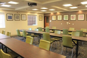 A conference room with multiple tables and chairs, framed artwork on the walls, and a window with blinds. - Holiday Inn Express & Suites Levelland by IHG (Levelland)
