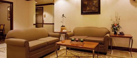 A living room with two sofas, a coffee table, a small table with a phone, and a wall clock.