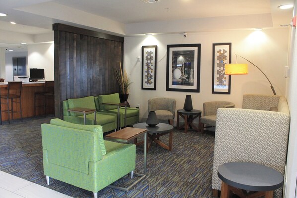 A hotel lobby with green seating, a bar area, and framed artwork on the walls. - Holiday Inn Express & Suites Levelland by IHG (Levelland)