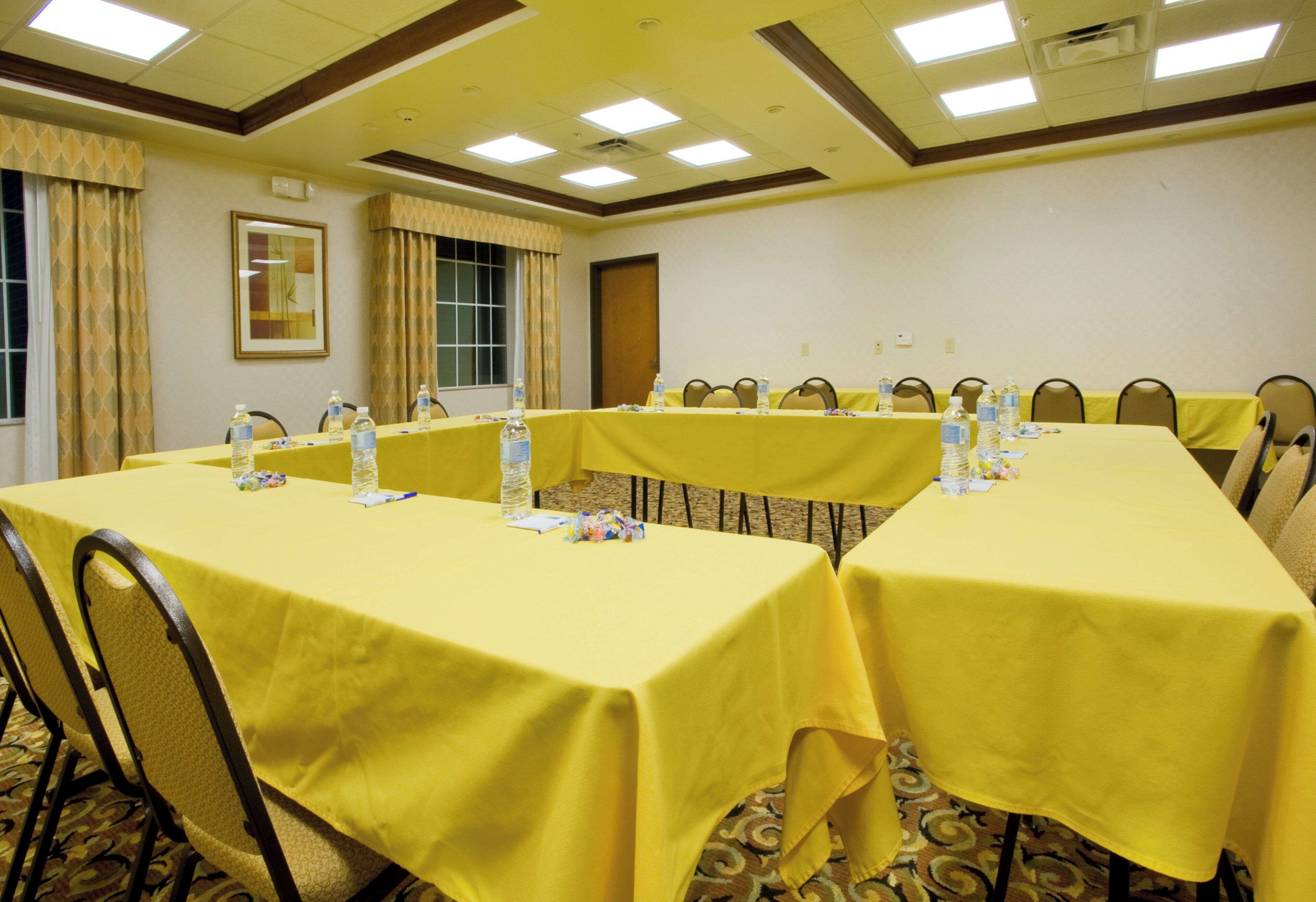 A conference room with yellow tables, chairs, and water bottles.