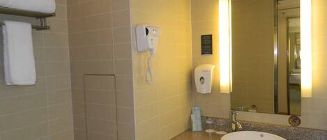 Une salle de bain équipée d’un lavabo, d’un miroir, d’un porte-serviettes et d’un sèche-mains.
