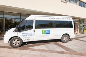 A white van parked in front of a building with large windows. - Holiday Inn Express Airport Tianjin by IHG (Tianjin)