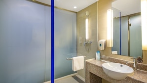 A modern bathroom with a glass shower enclosure, a sink with a mirror, and a towel rack. - Holiday Inn Express Airport Tianjin by IHG (Tianjin)