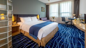 A hotel room with a large bed, a desk, a chair, a TV, and a window with curtains. - Holiday Inn Express Airport Tianjin by IHG (Tianjin)