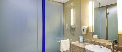 Une salle de bain moderne avec une douche à parois de verre, un lavabo doté d’un plan de travail en marbre et un grand miroir.