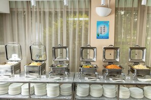 A buffet setup with multiple food dispensers and a stack of white plates. - Holiday Inn Express Airport Tianjin by IHG (Tianjin)