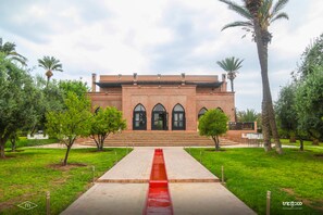 A building with a symmetrical facade, arched windows, and a central staircase leading to a red-tiled entrance.