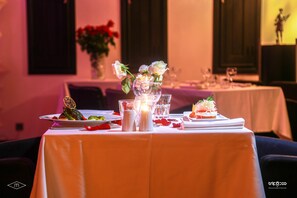 A table set for a meal with candles, glasses, and a vase of flowers.
