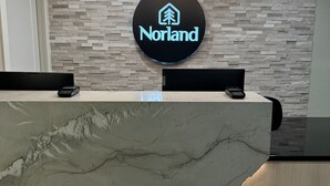 A reception desk with a modern design, a Norland logo, and a unique marble countertop. - Norland Inn and Suites Roseau (Roseau)