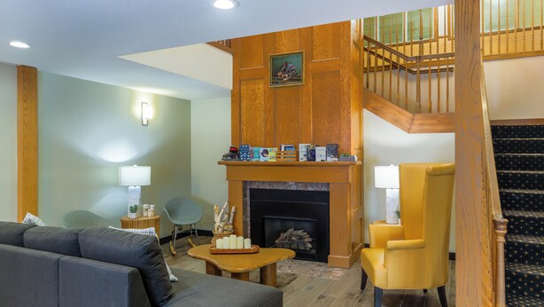 A living room with a fireplace, a sofa, a chair, and a staircase. - Norland Inn and Suites Roseau (Roseau)