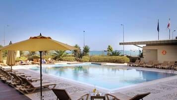 Una piscina al aire libre, sombrillas, tumbonas