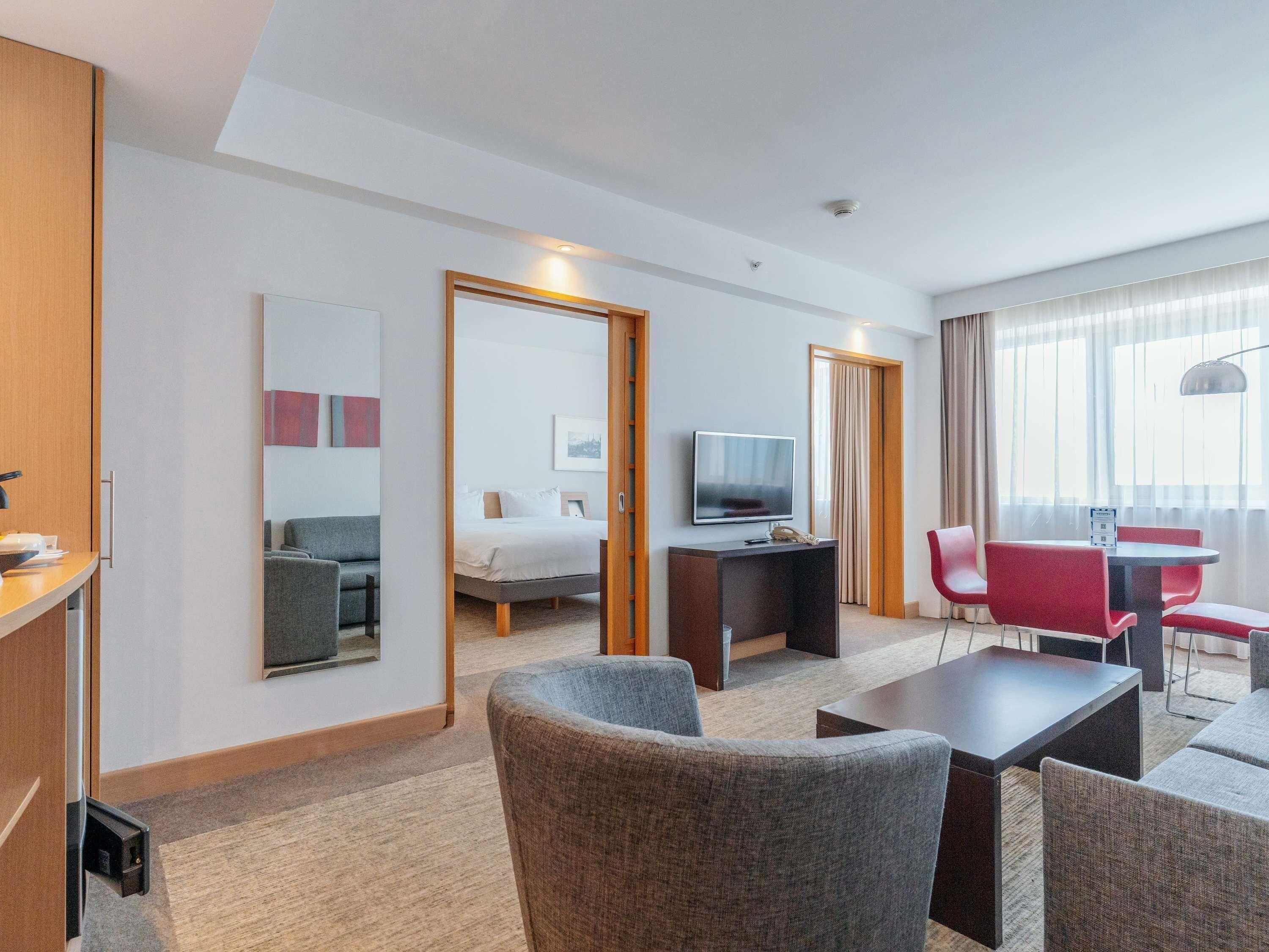 A hotel room with a bed, a TV, a desk, a chair, and a sofa.