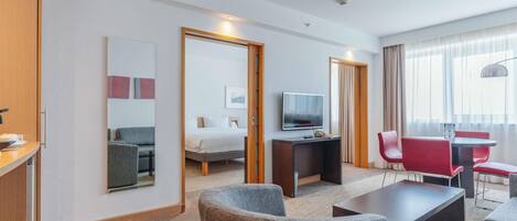 A hotel room with a bed, a TV, a desk, a chair, and a sofa.