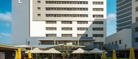 A Novotel hotel with a swimming pool, sun loungers, and umbrellas.