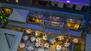An aerial view of a hotel courtyard with multiple dining areas, a swimming pool, and a stage with a circular platform. - Novotel Istanbul Zeytinburnu (Istanbul)