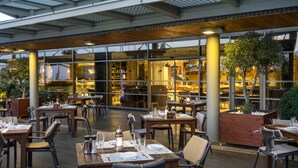 An outdoor dining area with tables and chairs, a wooden ceiling, and large windows. - Novotel Istanbul Zeytinburnu (Istanbul)