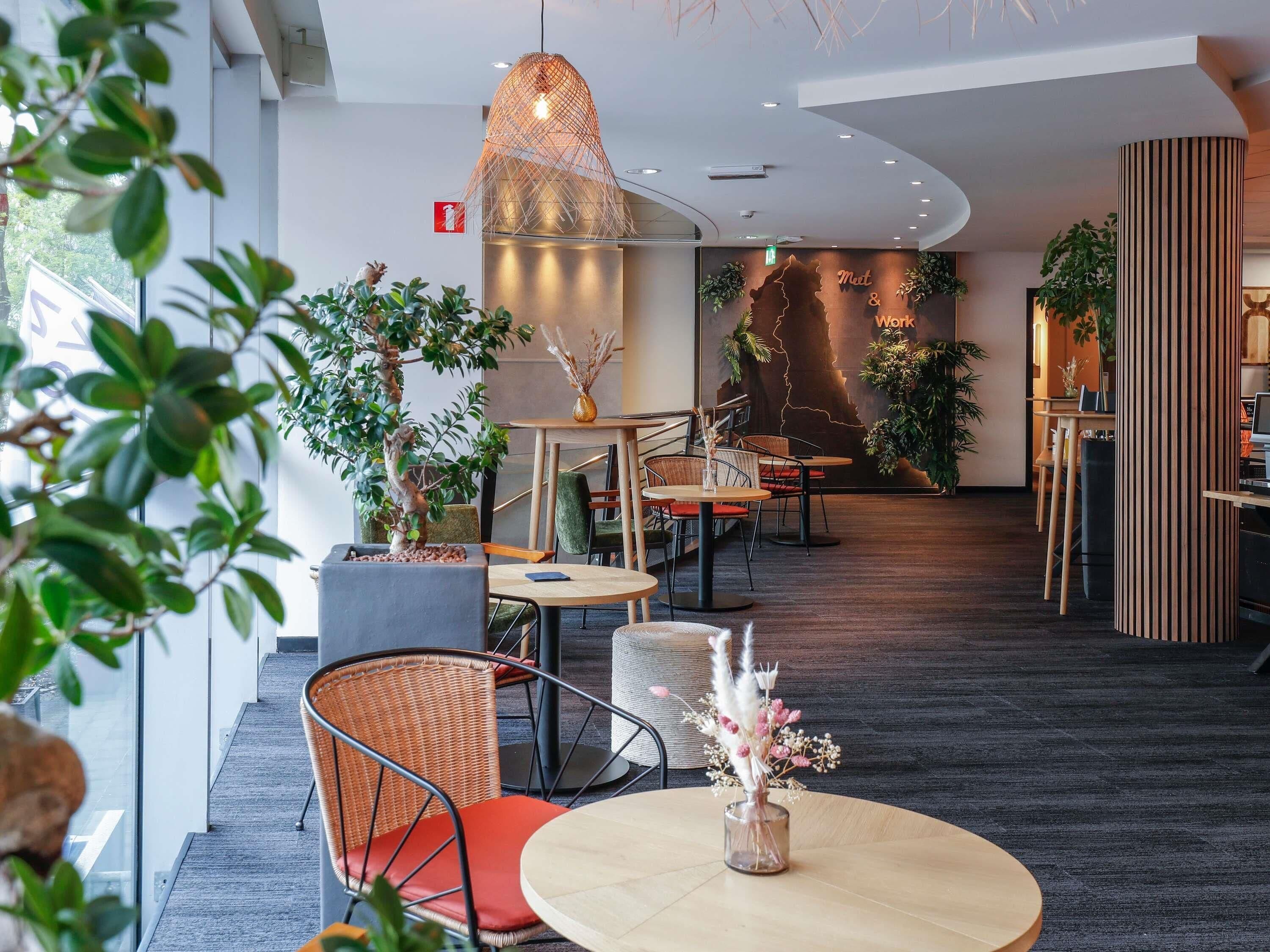 A modern interior with round tables, wicker chairs, and potted plants.