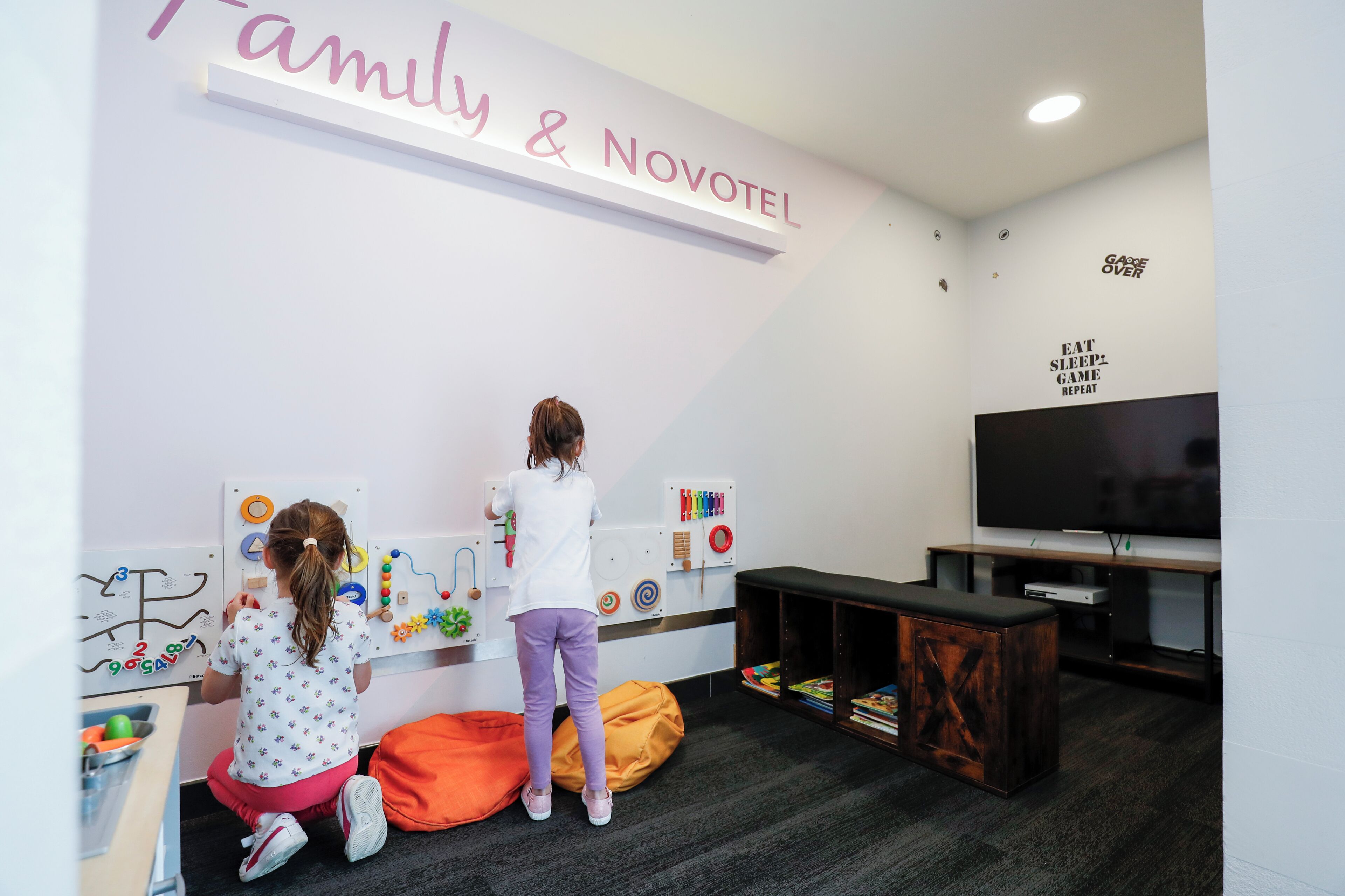 Ein Kinderspielbereich mit Lernspielzeug, einem Fernseher und einem Sofa.
