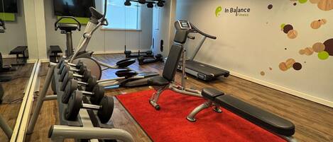 Ein Fitnessstudio mit Trainingsgeräten, einem roten Teppich und einer Wand mit einem Logo.