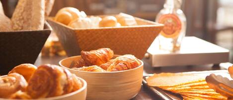 Un bufé de desayuno con diversas opciones de panadería, incluyendo pan, cruasanes y bollería.