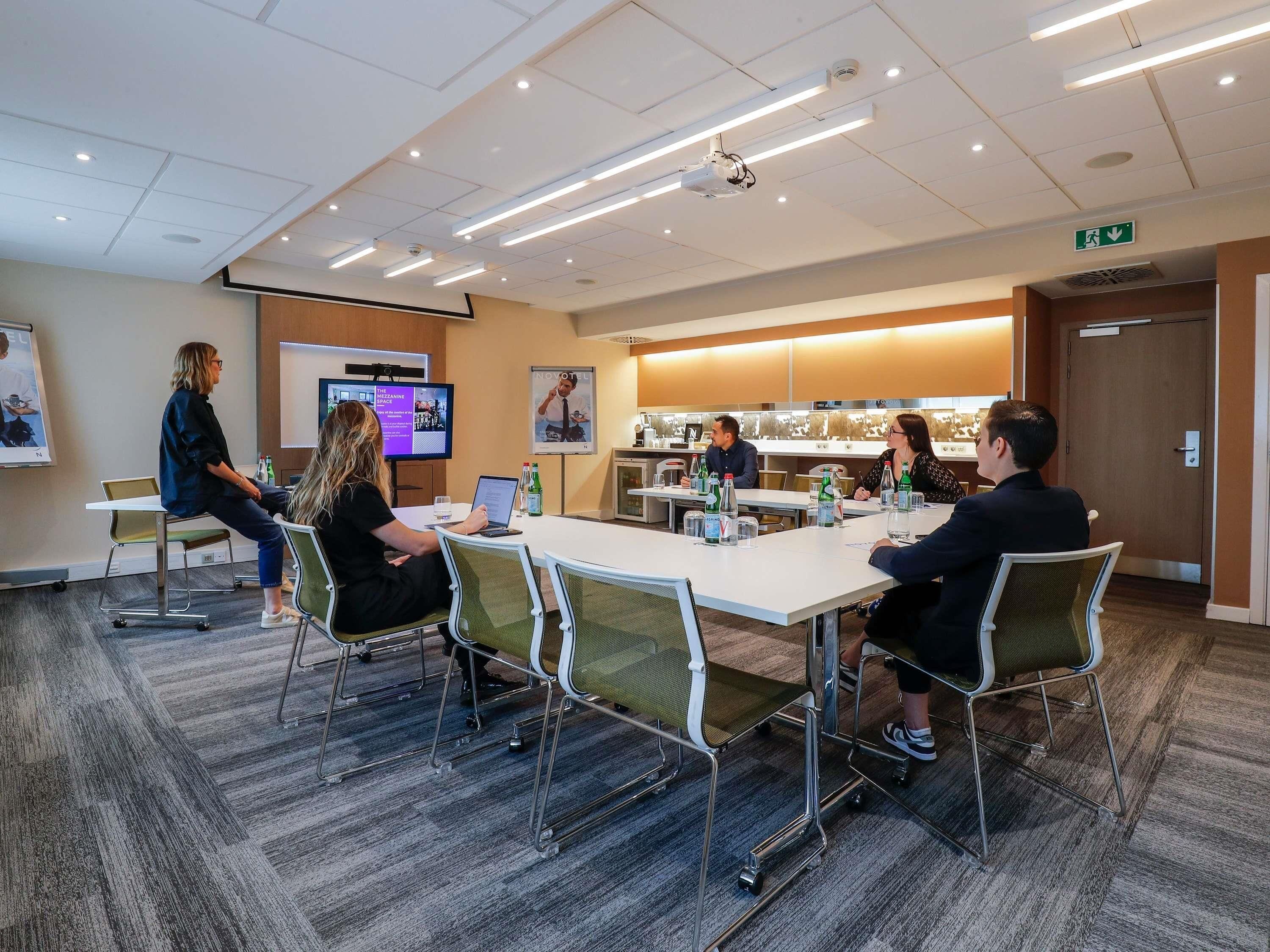 A conference room with a projector, a large screen, and a presentation on the wall.