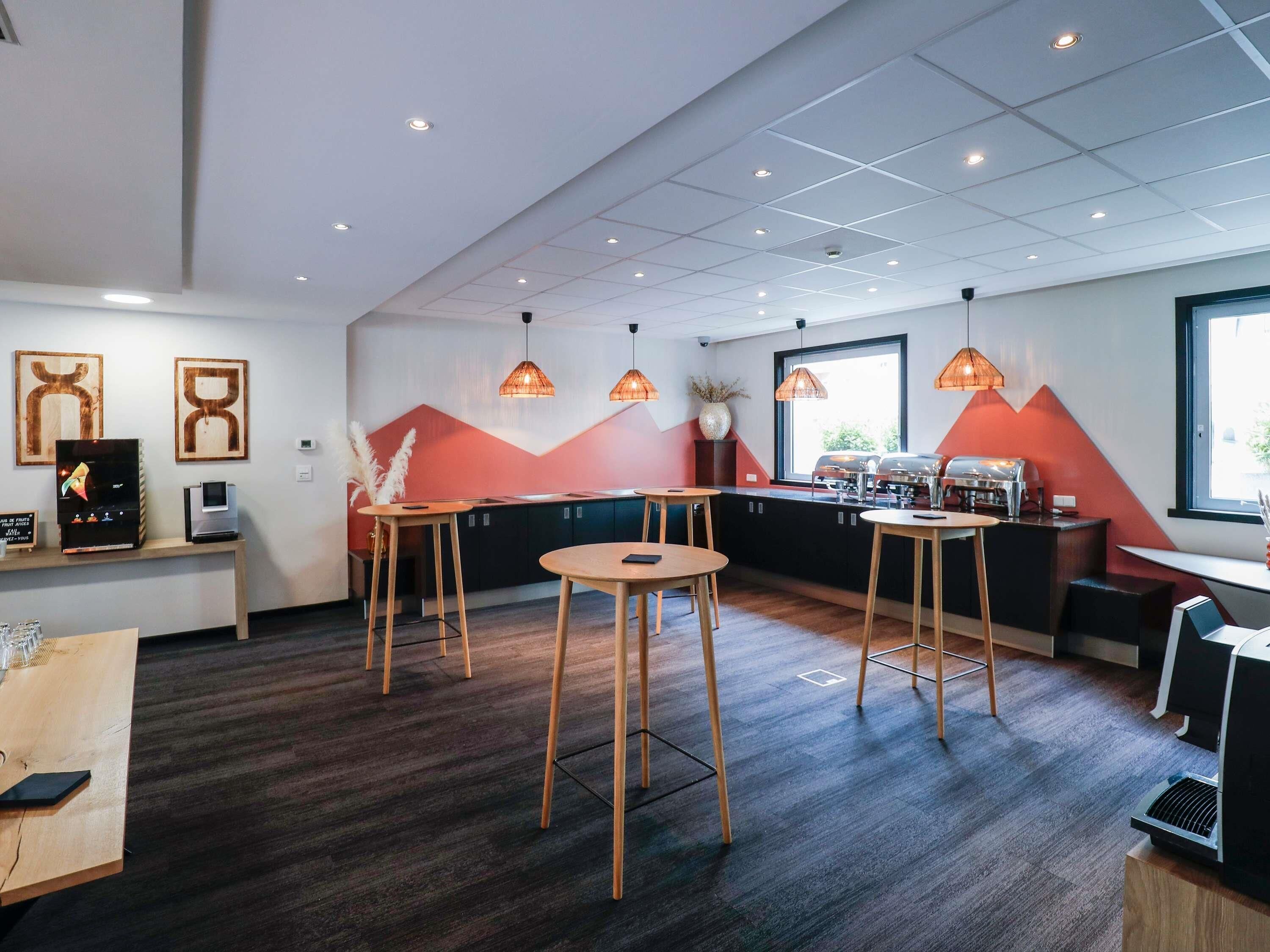 A modern restaurant interior with wooden stools, a bar area, and pendant lighting.