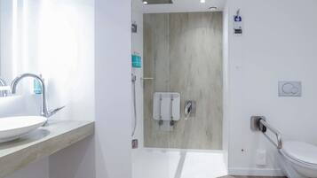 Une salle de bain moderne équipée d’un lavabo, de toilettes et d’une douche.