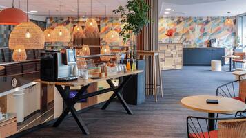 A modern cafe with a wooden counter, wicker chairs, and hanging rattan lamps.