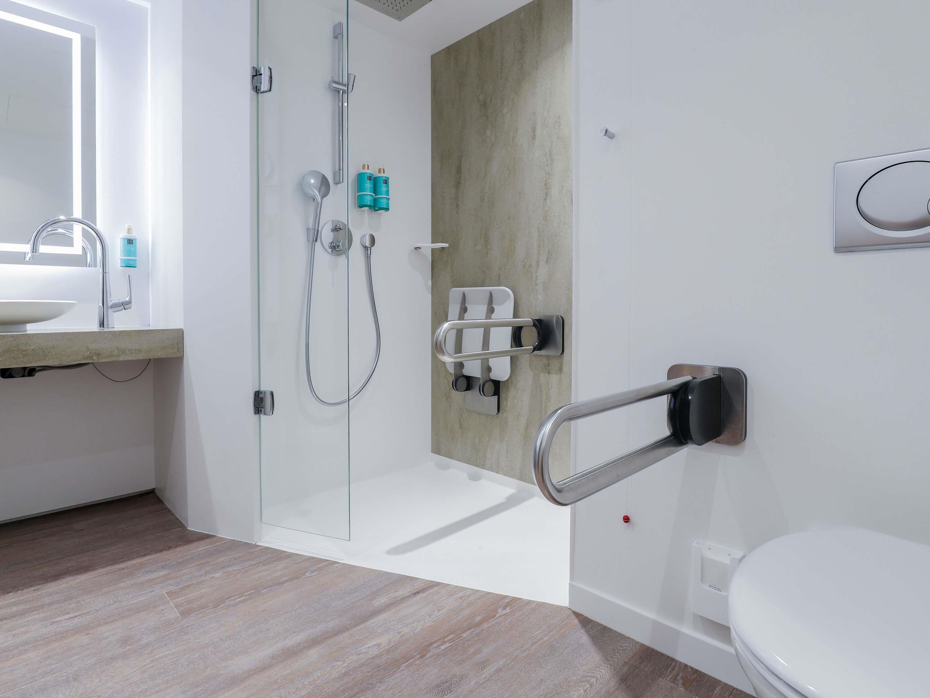 A modern bathroom with a glass shower enclosure, a toilet with a bidet attachment, and a sink with a faucet.