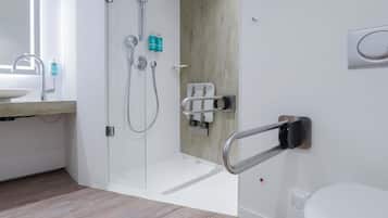 A modern bathroom with a glass shower enclosure, a toilet with a bidet attachment, and a sink with a faucet.