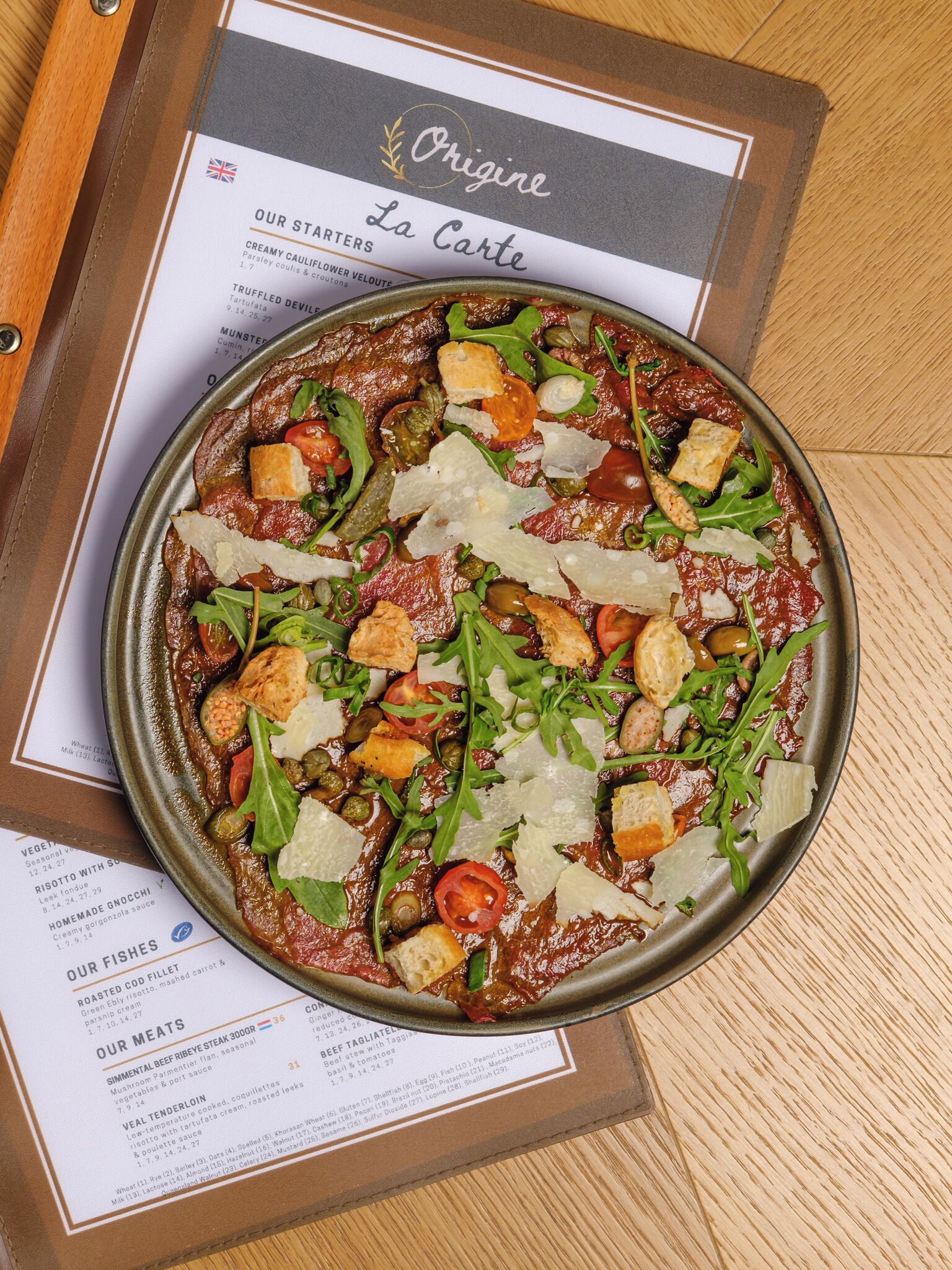 A menu with a dish that includes meat, vegetables, and cheese.