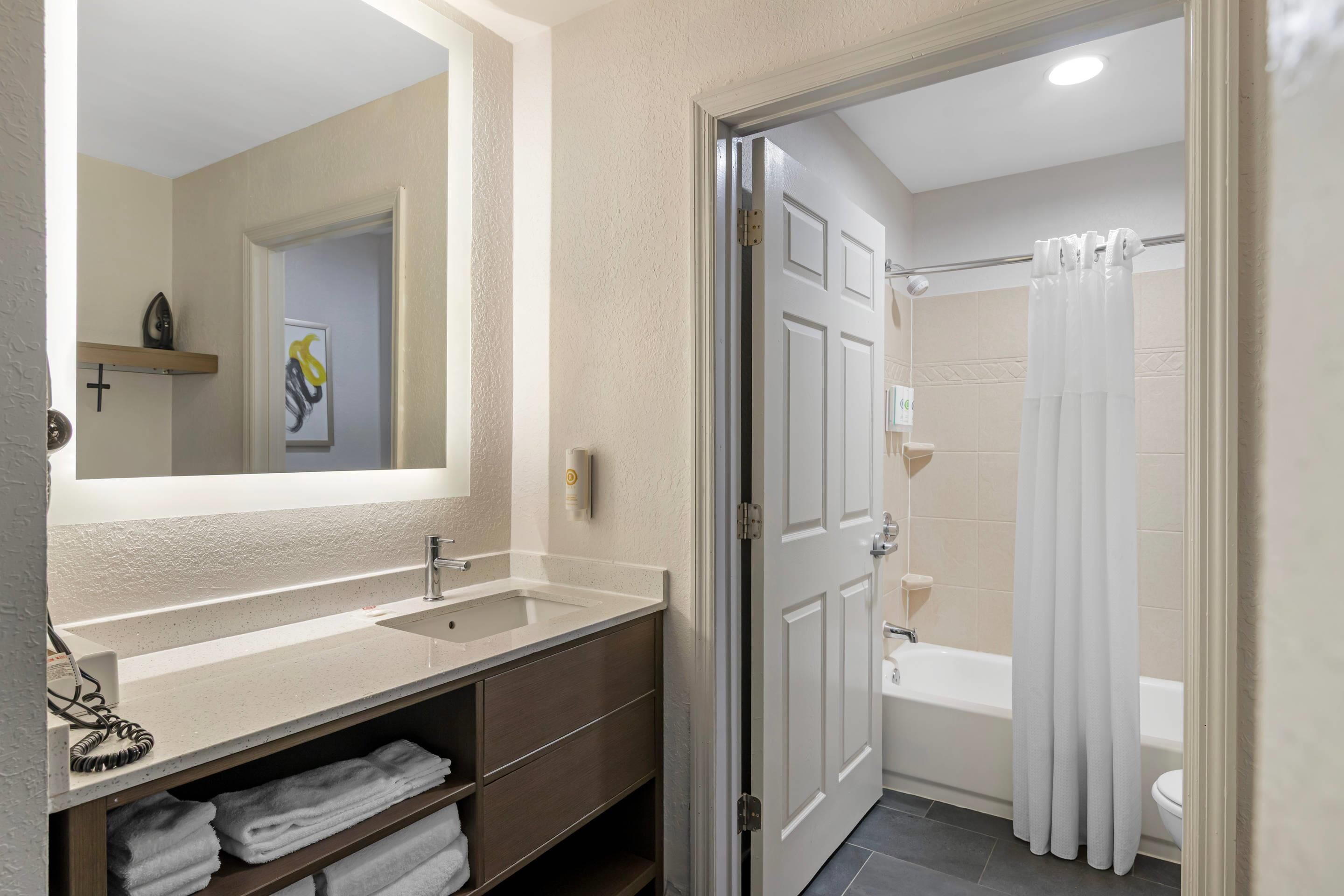 A bathroom with a double sink, a mirror, a shower curtain, and a toilet.