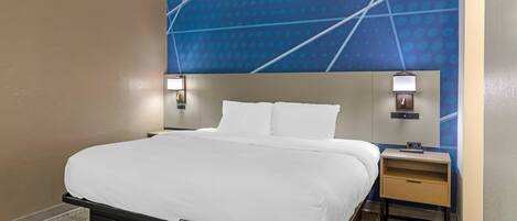 A hotel room with a bed, nightstands, a wall clock, and a patterned wall.
