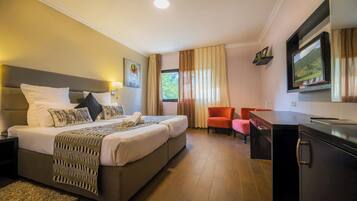 Habitación de hotel con cama, escritorio, silla y televisor.