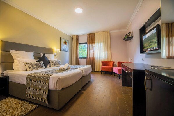 A hotel room with a bed, a desk, a chair, and a TV.
