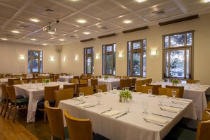 Banquet hall with round tables, white tablecloths, and comfortable seating.