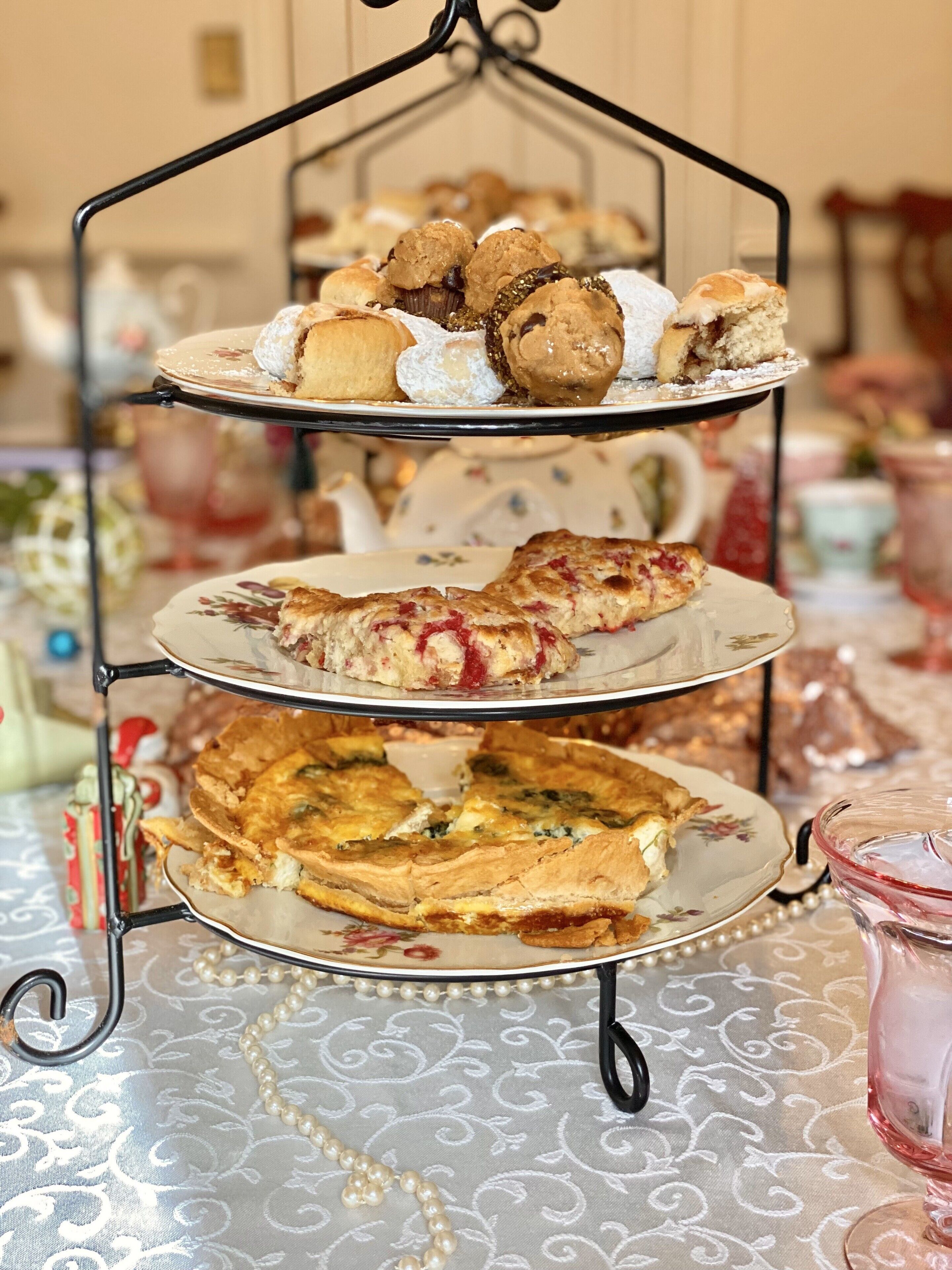 A three-tiered dessert stand with various pastries and a pie on a patterned tablecloth.