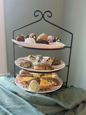 A three-tiered dessert stand with various pastries and a strawberry. - Colonial Gardens (Williamsburg)