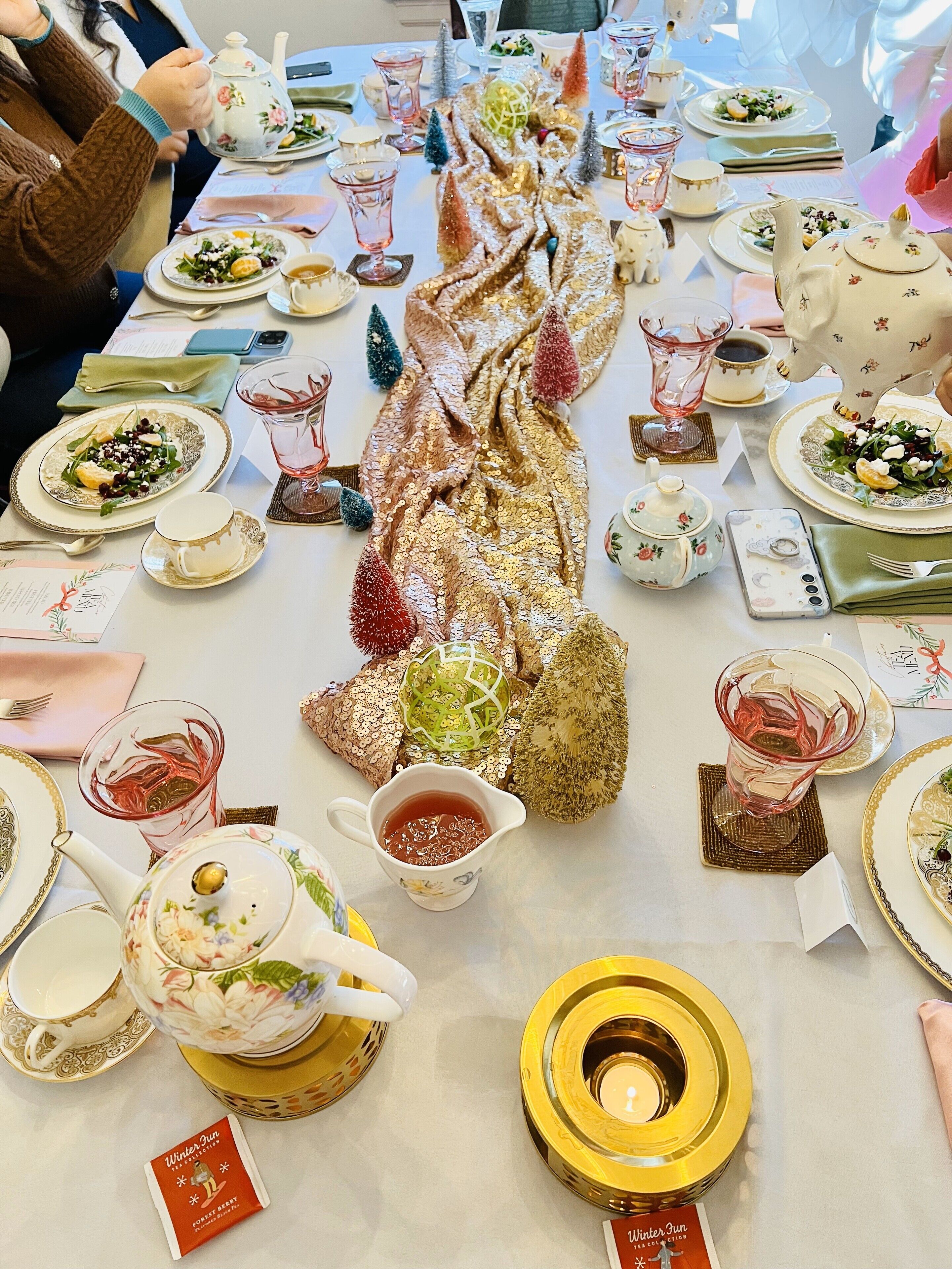 Una mesa dispuesta para una comida con varios platos, teteras y elementos decorativos.